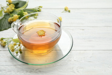 Cup of tea and linden blossom on white wooden table. Space for text