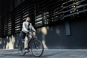 Tuinposter Businessman riding bicycle in front of modern office building. © Zoran Zeremski