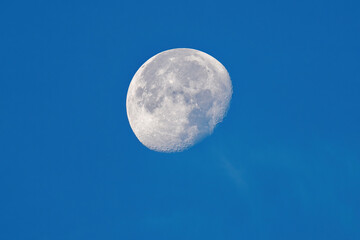 waning moon on day on a blue clear sky