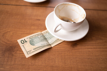 empty cap and ten dollars on woden table at cafe
