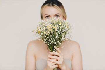Young and beautiful blonde woman with daisies bouquet. Natural eco cosmetics concept