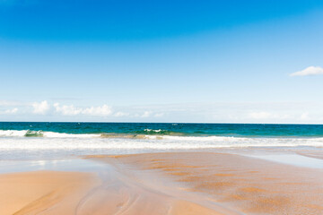 Fototapeta na wymiar Ocean waves and sandy beach on a sunny day. Nature tropical background. Kellys Beach, QLD, Australia