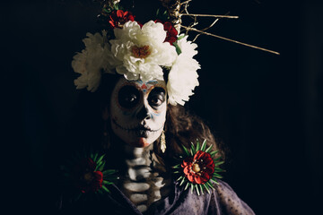 Woman with mexican skull halloween makeup on face. Day of the dead aka Dia de los Muertos and halloween concept.