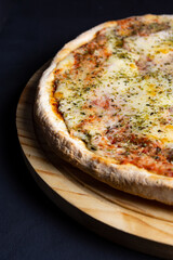 pizza con fondo negro de muzarella y oregano recien horneada