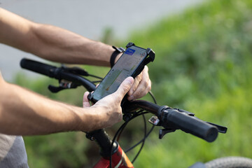 Man planning route using GPS navigation application in mobile phone on his bicycle bike. Plugging device
