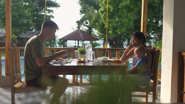 Family having breakfast at a resort restaurant on vacation in Southeast Asia.