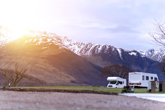 Caravan/motorhome against a wild backdrop of snow-capped mountains, with atmospheric glow effect 