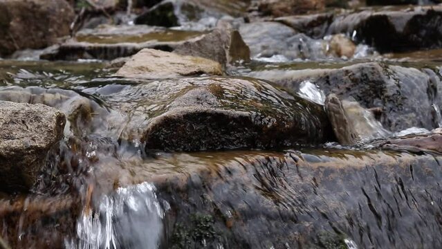 Slow motion of mountain stream with crystal clear rushing water. Selective focus