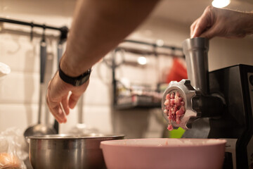 Mincer machine with fresh chopped meat at home kitchen. Preparing ground meat male hands closeup.