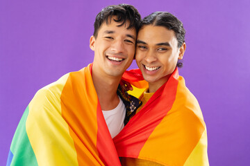Portrait of happy biracial male couple embracing and holding lgbt flag on purple background - Powered by Adobe