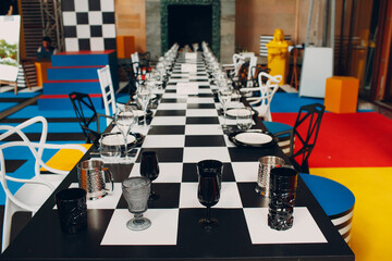 Wedding table decor like a chessboard with black and white dishes glasses.