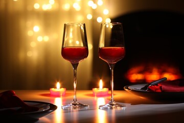 Glasses of wine and candles on table against blurred lights. Romantic dinner