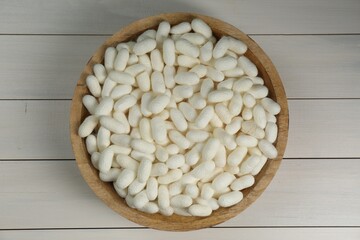 Silk cocoons in bowl on white wooden table, top view