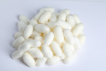 Fototapeta na wymiar Pile of natural silkworm cocoons on white background, above view