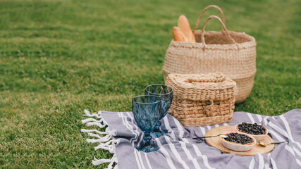 Beautiful romantic picnic with cake and two glasses of wine on the green meadow.