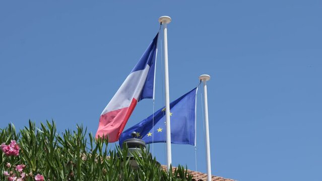 French and European flags waving in front of a clear blue sky. French flag waving. European flag waving. 