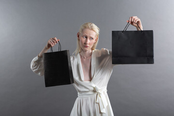 White caucasian albino blond woman holds shopping bag. Sale and discounts on market and Black Friday concept. - obrazy, fototapety, plakaty