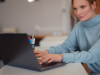 Business woman in blue dress working in office. Online business, young professional in workplace. using laptop sitting at table. learning to watch online webinar