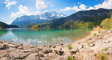 rocky bathing beach at lake shore Eibsee, view to Zugspitze mountain, upper bavarian summer landscape