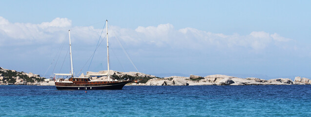 Horizontal banner or header with luxury sailing ship moored in turquoise water sea of wild Sardinia...
