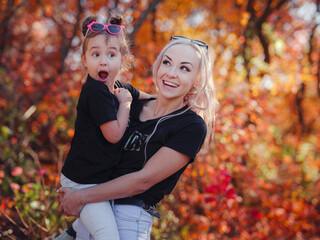 Beautiful young happy mother with little girl. Closeup of happy family on walk in foerest in sunshine. Happy family on autumn walk.