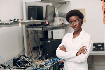 Scientist african american woman standing and looking at camera in laboratory with electronic tech instruments. Research and development of electronic devices by color black woman.