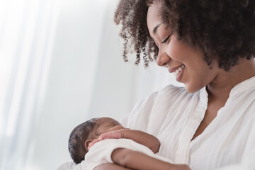 Close up portrait of beautiful young African American  mother holding sleep newborn baby in...