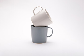 Two cups on a white background. One cup of milk color and one gray cup