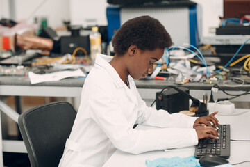 Scientist african american woman working in laboratory with computer and typing scientific text. Research and development of electronic devices by color black woman.