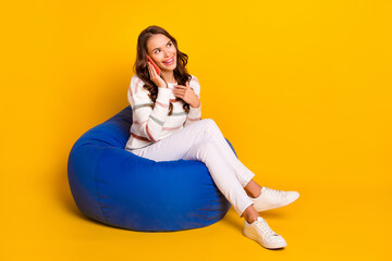 Full size photo of young pretty cute lady sitting pouf talking telegram call look empty space...