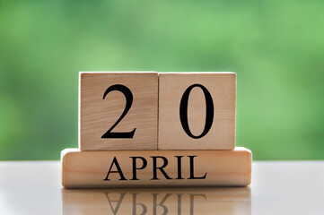 April 20 calendar date text on wooden blocks with blurred park background. Copy space and calendar concept