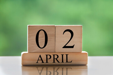 April 2 calendar date text on wooden blocks with blurred park background. Copy space and calendar concept