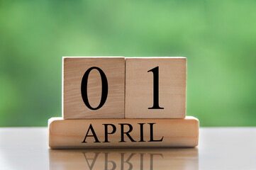 April 1 calendar date text on wooden blocks with blurred park background. Copy space and calendar concept