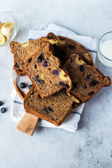 Banana bread slices with blueberries served on a wooden board on a gray background. Top view.