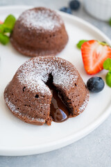 Chocolate fondant lava cake with fresh berries on a plate on a gray background.