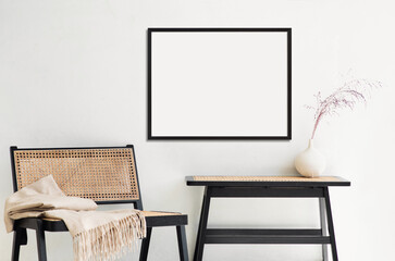Blank frame mockup in modern interior design with trendy vase and chair on empty white wall...