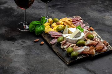 Antipasto board Platter with Spanish ham jamon serrano or Italian prosciutto crudo, Italian hard cheese pecorino toscano on a dark background. top view