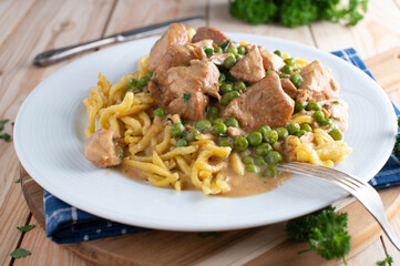 Turkey goulash with cream sauce, german spaetzle noodles and green peas on a plate