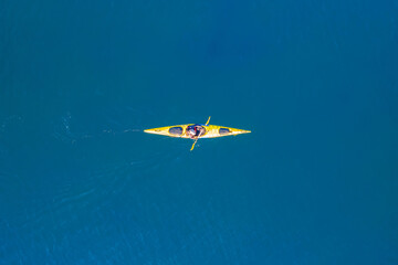 Yellow kayak rowers on blue turquoise water sea, sunny day. Concept extreme sport, aerial top view
