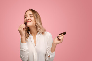 Happy young lady smelling yummy chocolate bar in studio