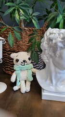 Knitted handmade toy white cat sits on a dark table in the interior of a beautiful bright room. Hobby knitting crochet toys. Children's room or children's cafe. Luxurious interior.