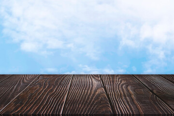 Wooden board empty table in front of blurred background. Perspective dark brown wood over blurred blue sky, can be used for display or montage your products. Mock up for display of product.