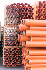 Background of orange plastic sewage pipes used at the building site. Texture and pattern of plastic drainage pipe. Light through tubes.