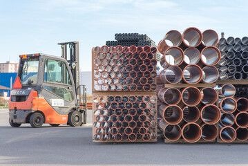 Olomouc October 10th 2021 czech Rep. Forklift parked next to orange plastic sewage pipes used at the building site. Texture and pattern of plastic drainage pipe. Light through tubes.