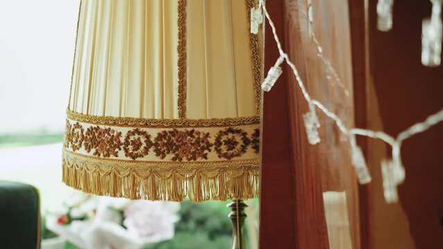 Vintage style floor lamp torchere with bell shape fringed drapery shade being switched on and off by pulling a chain, slow motion.