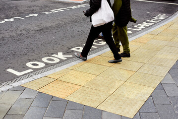 Tactile tiles for the blind. Panels for the blind laid on asphalt. Guide tape for the disabled. People cross the road at a traffic light for the blind.