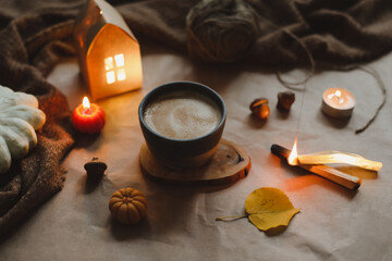 Autumn cozy home interior with a cup, candles, plaid. Hygge home decor. Halloween and Thanksgiving concept 