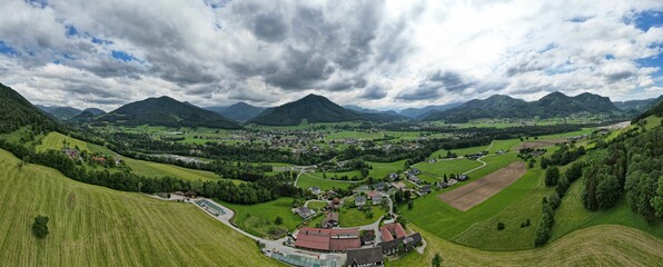 Aerial panoramic shot of a hillside with forest and houses in the foothills