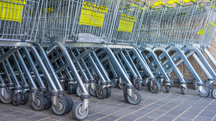 Many metal shopping carts on a parking lot near supermarket outdoors. Shopping concept. Shopping carts outside.