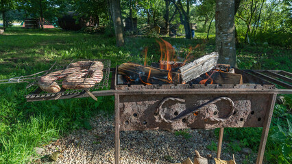 Tasty homemade sausage made of beaver meat cooking on grill. Beaver meat sausages are cooked on coals.